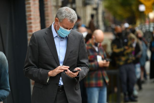 Mayor Bill de Blasio stares at his smartphone while waiting to vote in Park Slope on Tuesday.